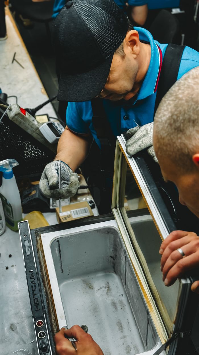 Technicians repairing a refrigerator unit